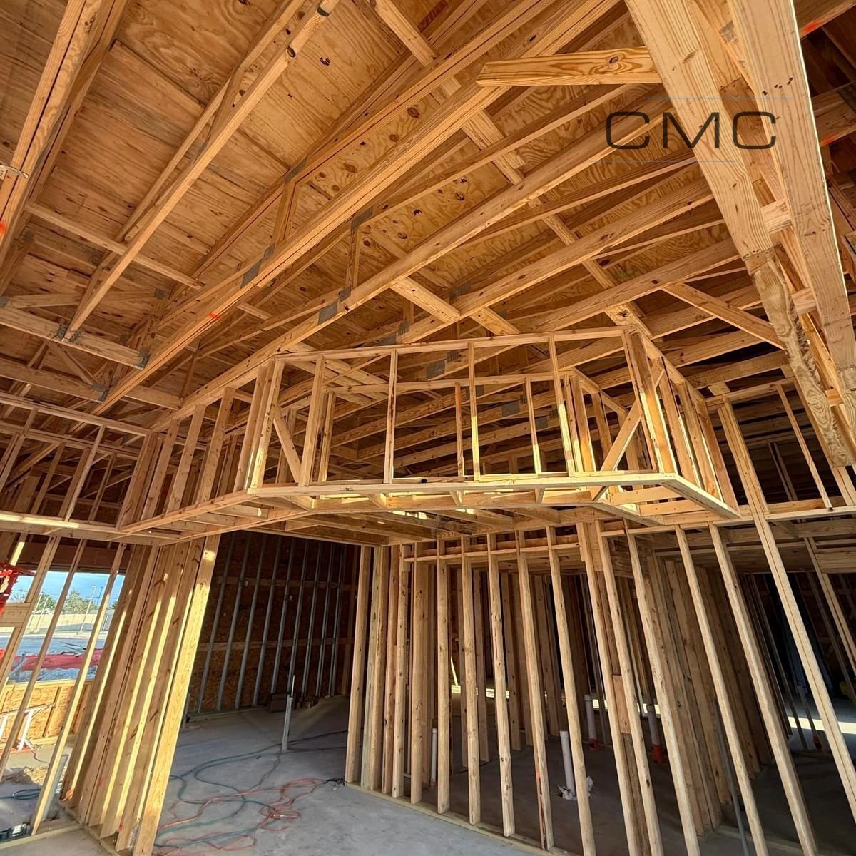 Interior of a wood-framed house under construction showing exposed wooden beams and wall framing