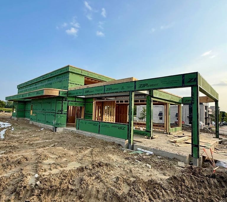 Green metal frame commercial building under construction on sandy ground with clear blue sky