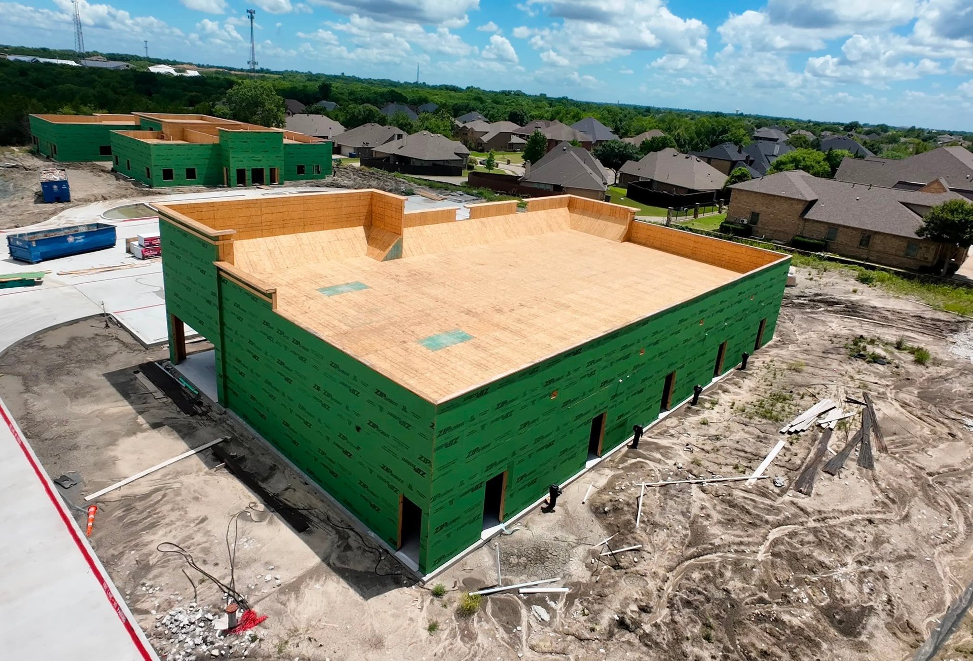 Green wooden construction building frame with plywood roof sheathing in a residential development area